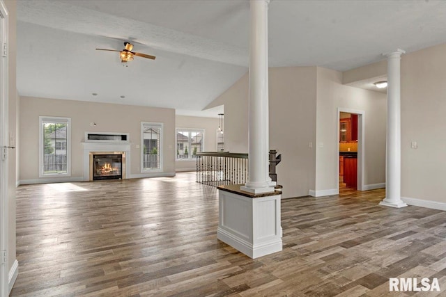 unfurnished living room with ornate columns, plenty of natural light, ceiling fan, and wood finished floors