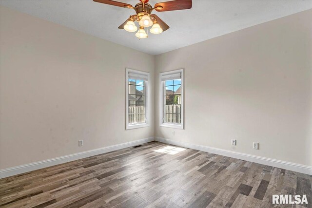 empty room featuring baseboards, ceiling fan, wood finished floors, and visible vents