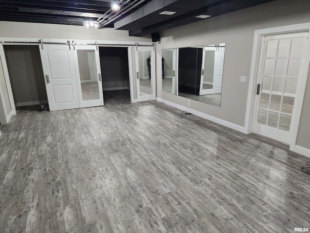 interior space featuring baseboards, a barn door, and wood finished floors