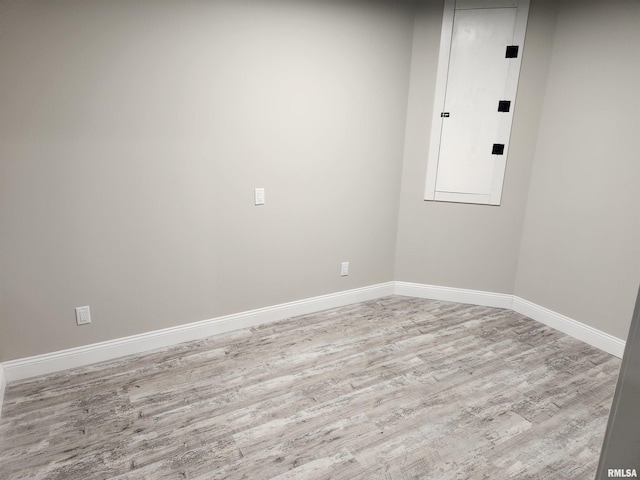 empty room featuring baseboards, electric panel, and wood finished floors