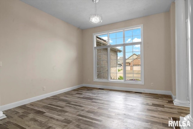 unfurnished dining area featuring baseboards, wood finished floors, and an inviting chandelier
