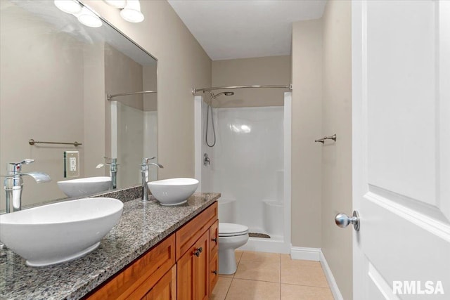 bathroom with double vanity, a sink, a walk in shower, and tile patterned floors