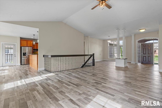 unfurnished living room with baseboards, a ceiling fan, light wood finished floors, and lofted ceiling