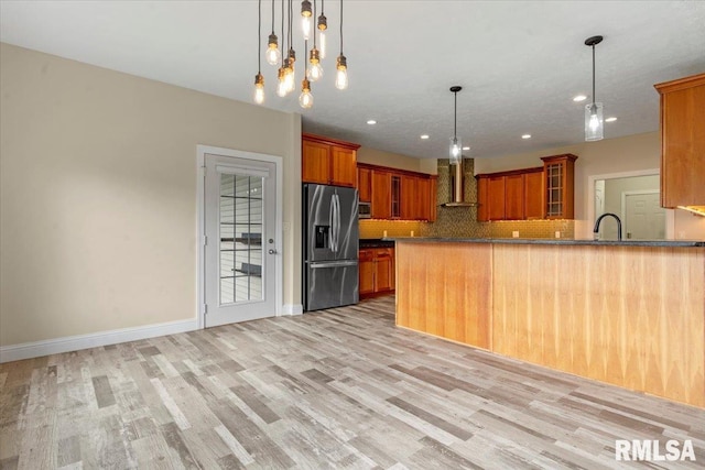 kitchen featuring appliances with stainless steel finishes, tasteful backsplash, brown cabinetry, and wall chimney exhaust hood