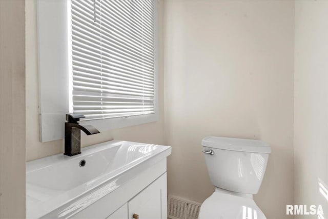 half bath featuring toilet, visible vents, and vanity