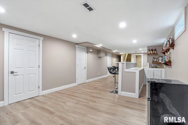 exercise area featuring light wood-type flooring, visible vents, indoor bar, and recessed lighting