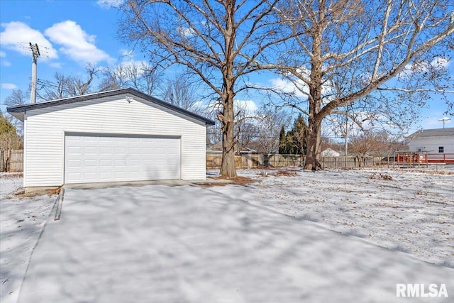 snow covered garage featuring fence