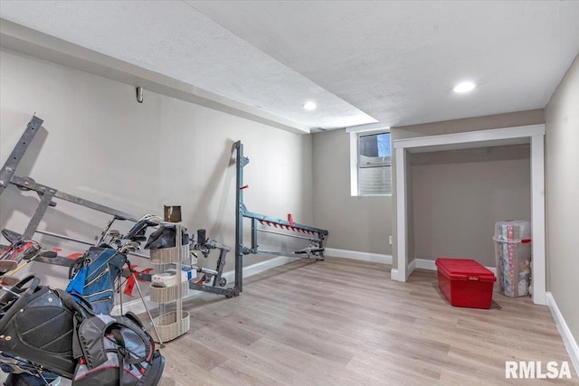 workout room featuring light wood-type flooring, baseboards, a textured ceiling, and recessed lighting