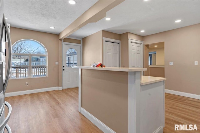 kitchen featuring light wood-type flooring, light countertops, a textured ceiling, and baseboards