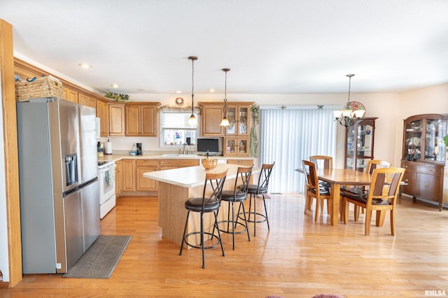 kitchen featuring decorative light fixtures, a kitchen island, light countertops, stainless steel refrigerator with ice dispenser, and glass insert cabinets