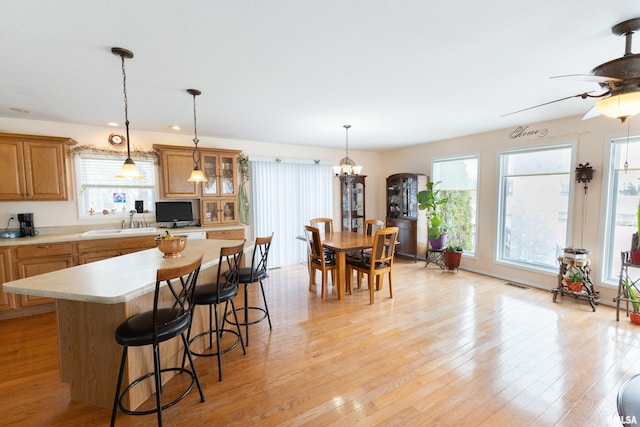 kitchen featuring light countertops, brown cabinetry, glass insert cabinets, and a center island