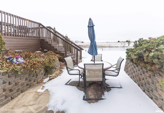 snow covered patio featuring stairs and outdoor dining area