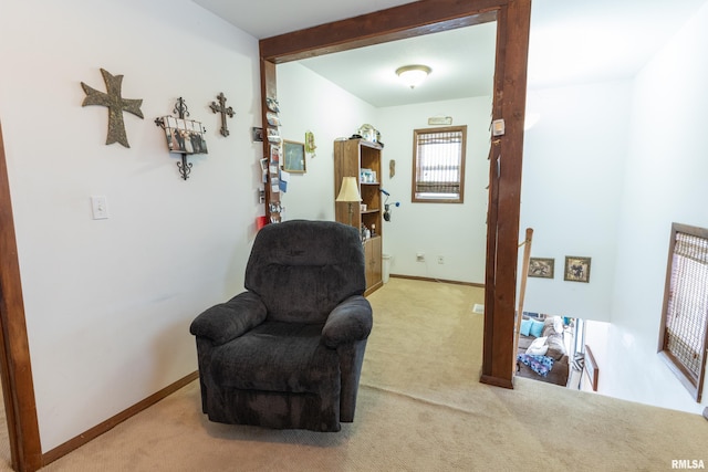 sitting room featuring carpet floors, baseboards, and beamed ceiling