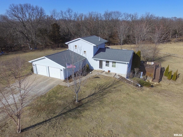 view of front of house with driveway, a forest view, a shingled roof, and a front yard