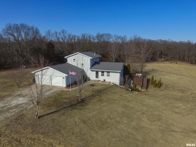 view of front of property featuring a front yard, concrete driveway, a forest view, and an attached garage