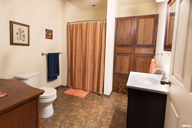 full bath with toilet, stone finish flooring, and vanity