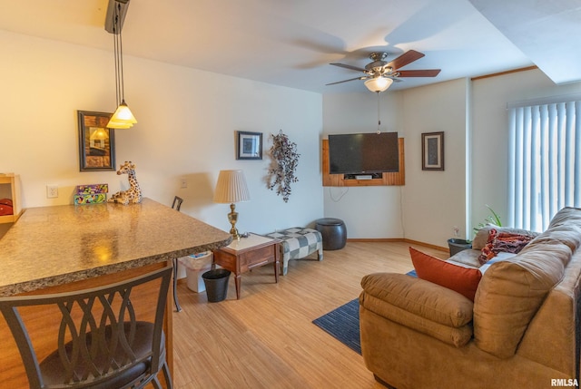 living area featuring ceiling fan, baseboards, and wood finished floors