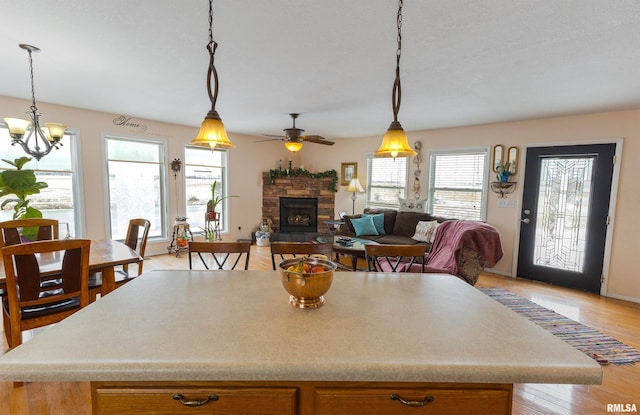 kitchen with a healthy amount of sunlight, light wood finished floors, open floor plan, and a stone fireplace