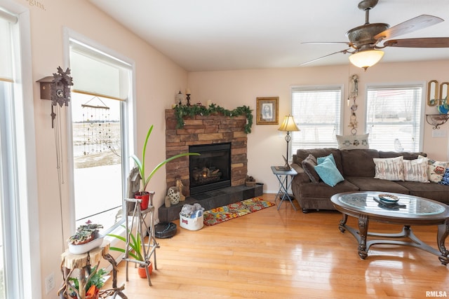 living area with ceiling fan, a fireplace, and wood finished floors