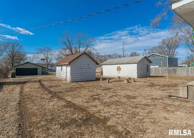 view of side of home featuring an outbuilding, a storage unit, a detached garage, and fence