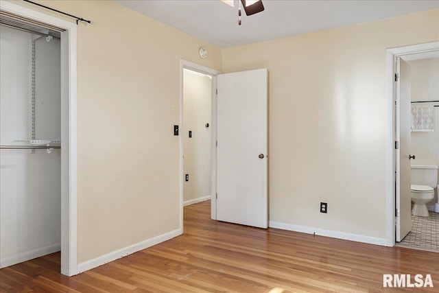 unfurnished bedroom with a closet, ensuite bath, baseboards, and wood finished floors