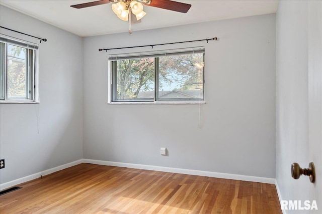 empty room featuring a healthy amount of sunlight, visible vents, baseboards, and wood finished floors