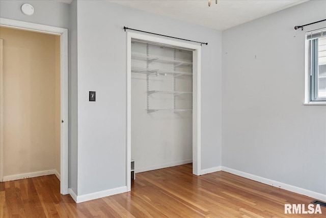 unfurnished bedroom featuring a closet, baseboards, and wood finished floors