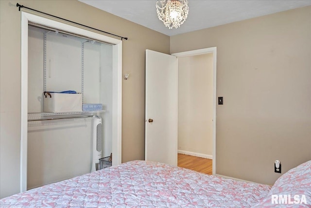 bedroom featuring a closet, wood finished floors, and a notable chandelier