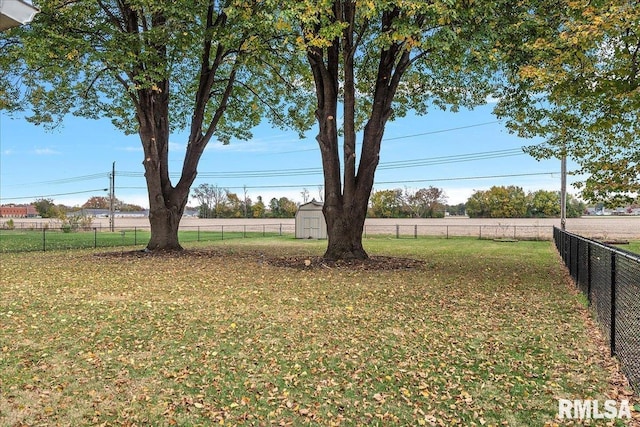 view of yard featuring fence, an outdoor structure, and a storage unit