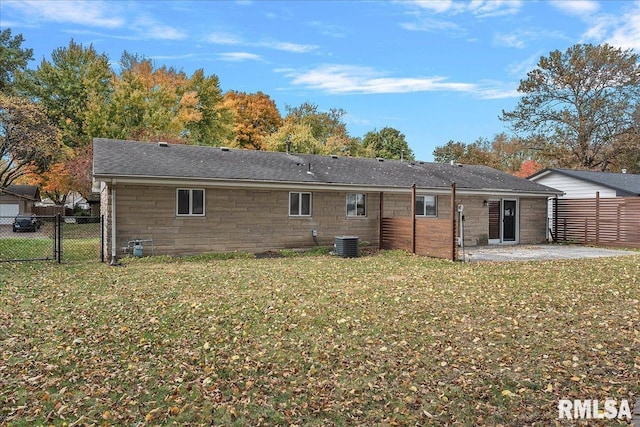 rear view of property featuring stone siding, a patio area, a lawn, and central AC