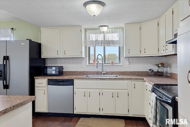 kitchen with tasteful backsplash, white cabinets, light countertops, black appliances, and a sink