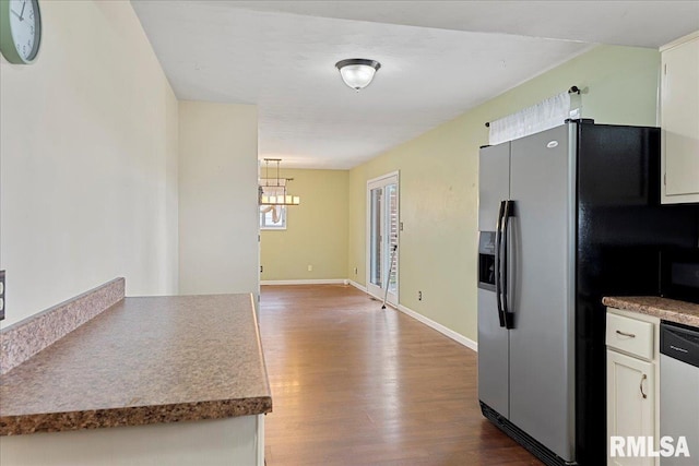 kitchen with stainless steel appliances, an inviting chandelier, white cabinetry, wood finished floors, and baseboards