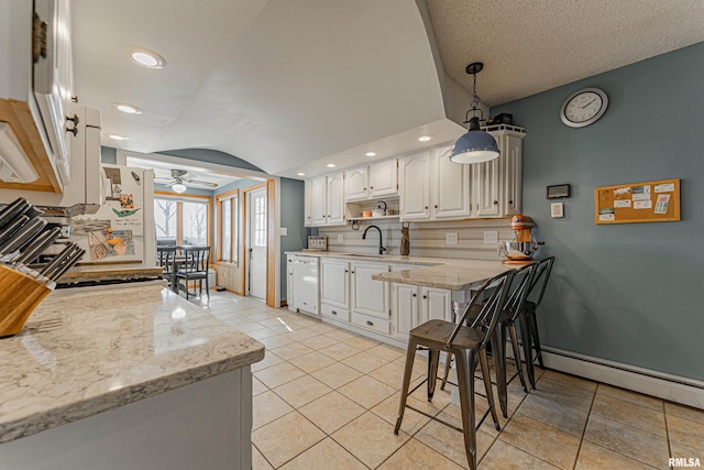 kitchen with light stone counters, a sink, white cabinetry, dishwasher, and pendant lighting