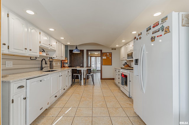 kitchen with white appliances, white cabinets, a sink, and light tile patterned flooring