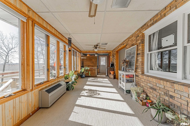 sunroom with ceiling fan, heating unit, visible vents, and a healthy amount of sunlight