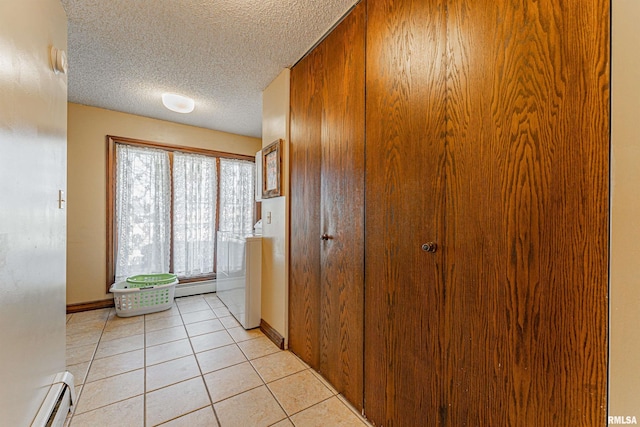 interior space with a textured ceiling, light tile patterned flooring, a baseboard heating unit, baseboards, and baseboard heating