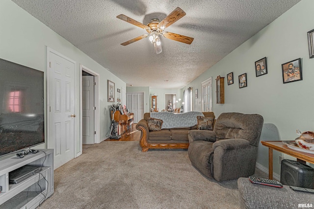 living room featuring light carpet, a ceiling fan, and a textured ceiling