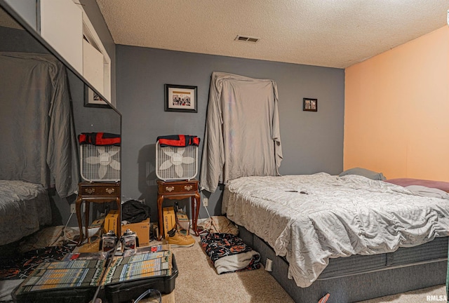 bedroom with carpet, visible vents, and a textured ceiling