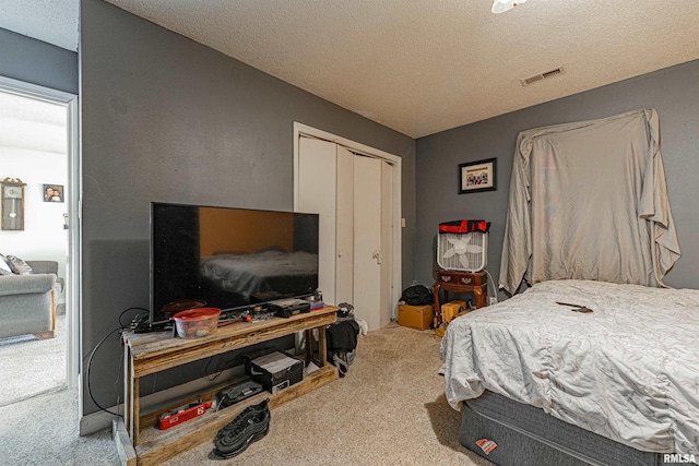 carpeted bedroom with a textured ceiling, visible vents, and a closet