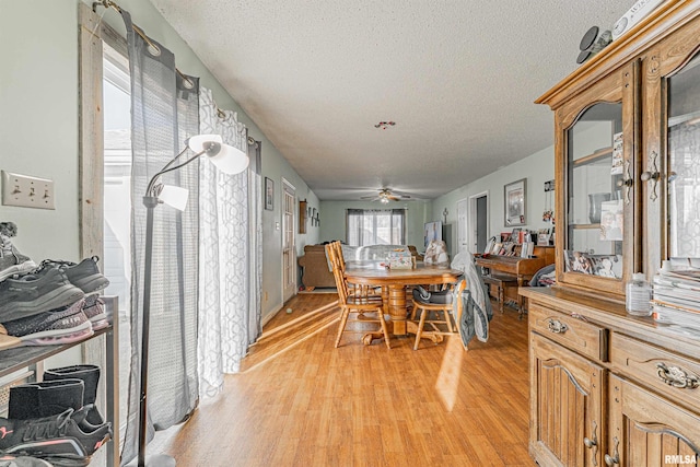 dining room featuring ceiling fan, light wood-style flooring, and a textured ceiling