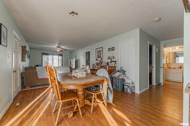 dining room featuring ceiling fan, a textured ceiling, baseboards, and wood finished floors