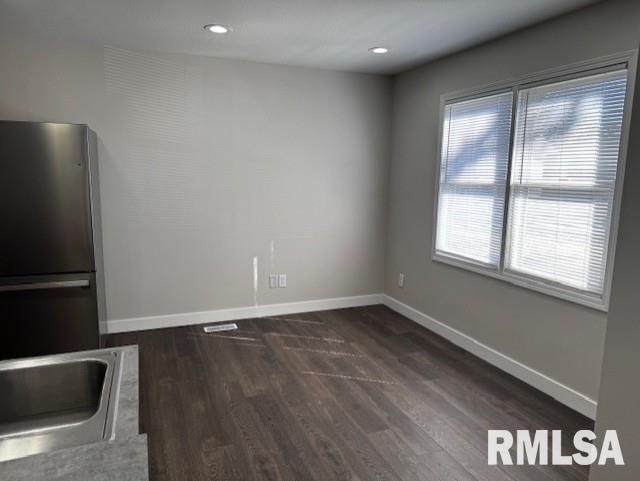 unfurnished dining area with dark wood-style floors, recessed lighting, a sink, and baseboards