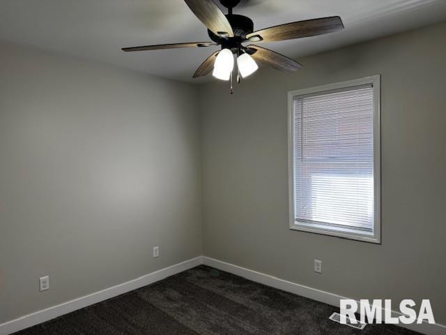 unfurnished room with a ceiling fan, dark colored carpet, and baseboards