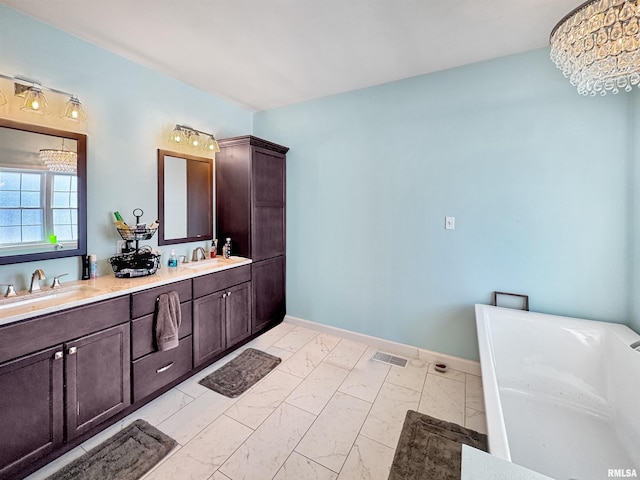 bathroom featuring a soaking tub, marble finish floor, a sink, and double vanity