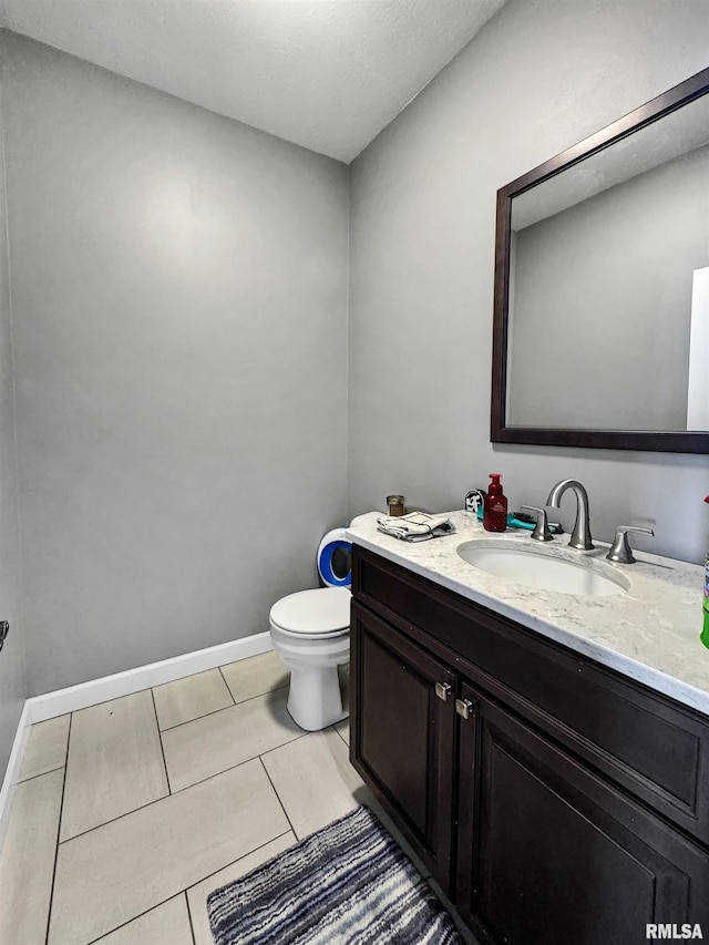 half bath featuring toilet, tile patterned flooring, baseboards, and vanity