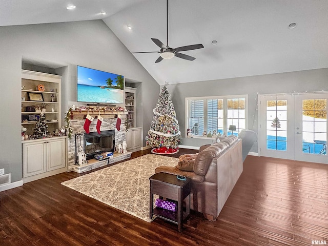 living room with french doors, a stone fireplace, dark wood finished floors, and built in features