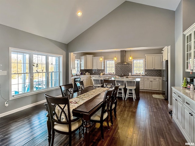 dining room with dark wood-type flooring, high vaulted ceiling, and baseboards