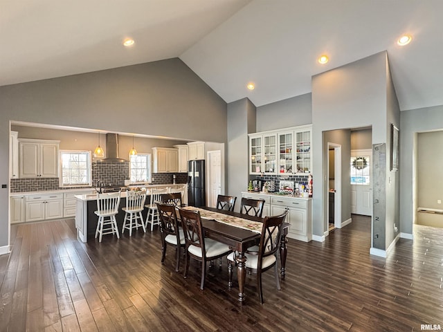 dining space featuring baseboards, high vaulted ceiling, dark wood finished floors, and recessed lighting