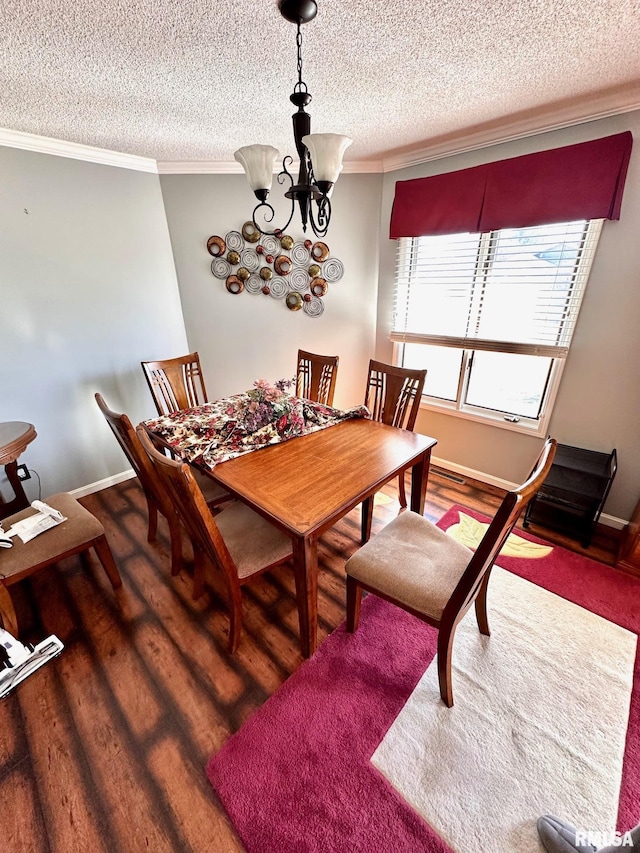 dining room featuring a textured ceiling, ornamental molding, wood finished floors, and an inviting chandelier