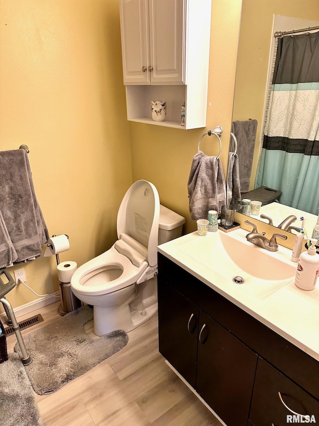 bathroom with toilet, visible vents, wood finished floors, and vanity